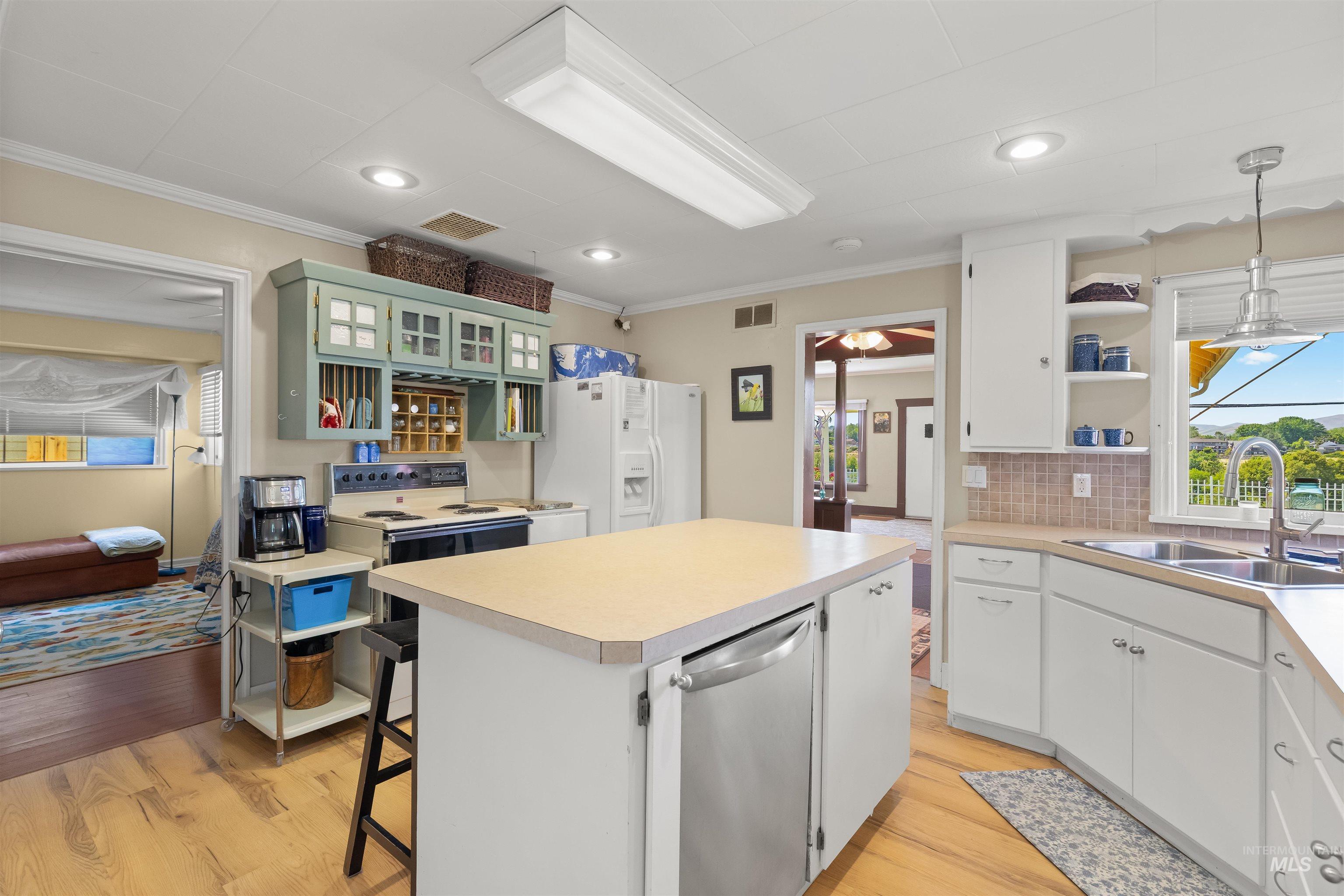 619 Prospect Avenue Lewiston, ID 83501 - Photo 15 of 37 Kitchen featuring wood-finish flooring, white cabinetry, a central island with integrated dishwasher, recessed lighting, and a window above the sink