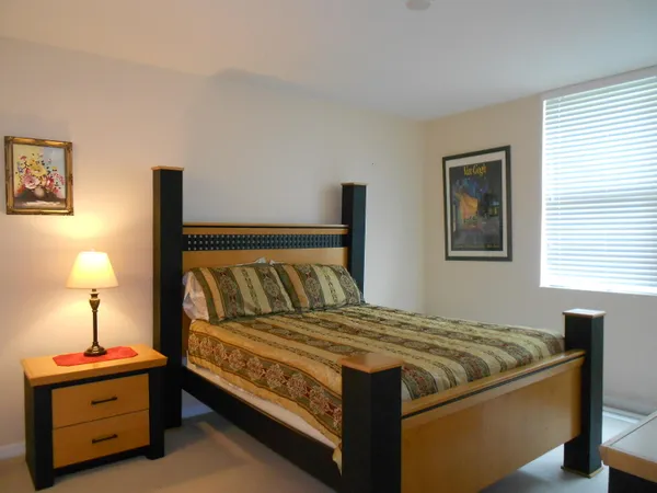 a bedroom with a bed and a lamp on dresser