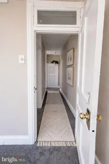 a view of a hallway with wooden floor and a living room