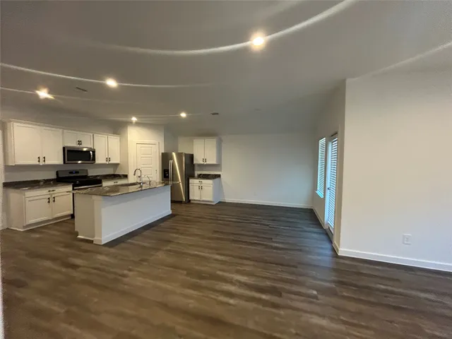 a view of kitchen with granite countertop refrigerator and stove top oven