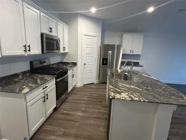 a kitchen with stainless steel appliances granite countertop a sink stove and refrigerator