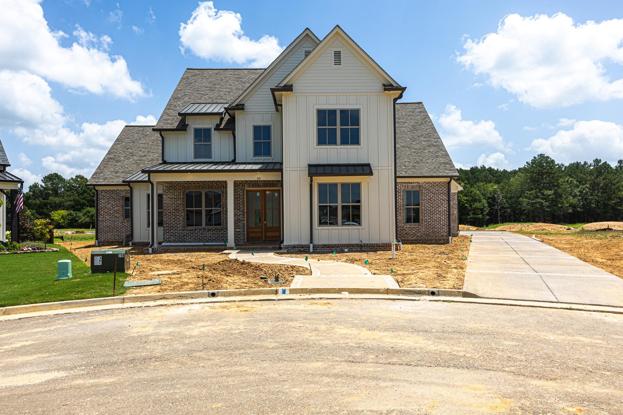 55 New Pond Road Piperton, TN 38017 - Photo 1 of 4 Modern farmhouse exterior featuring vertical white siding, brick accents, and a dark shingle roof