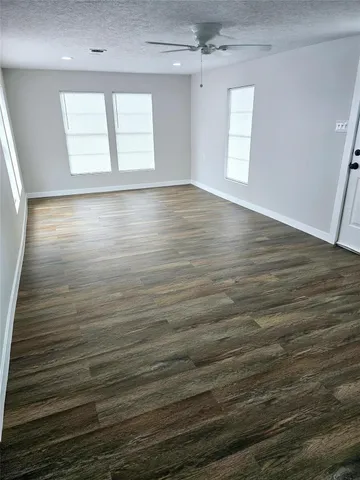 en empty room with wooden floor and windows