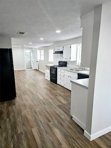 a kitchen with granite countertop white cabinets and black appliances