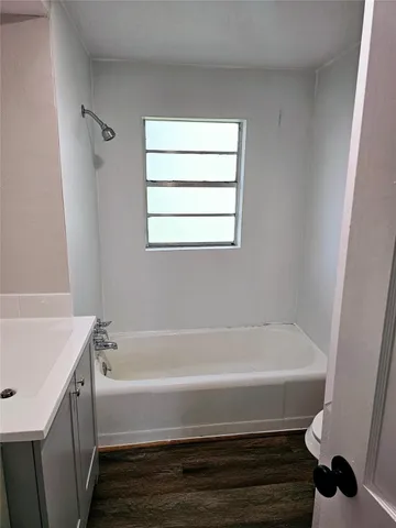 a view of an empty room with wooden floor and a chandelier