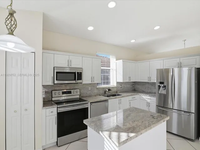 a kitchen with kitchen island granite countertop a refrigerator stove microwave and sink