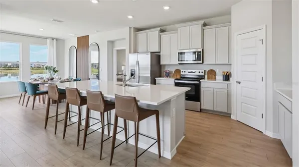 a large kitchen with cabinets chairs and refrigerator