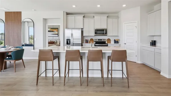 a dining area with stainless steel appliances kitchen island granite countertop a dining table chairs and a refrigerator