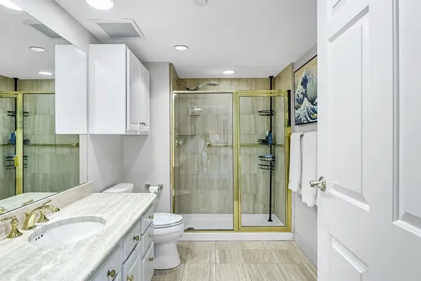 a bathroom with a granite countertop sink toilet and shower