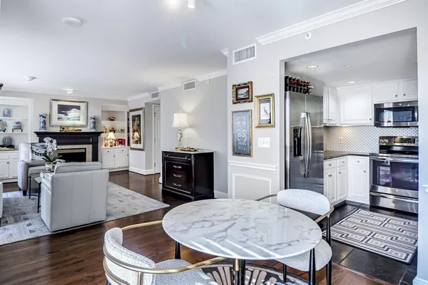 a kitchen with stainless steel appliances kitchen island granite countertop a refrigerator a stove a sink a dining table and chairs with wooden floor