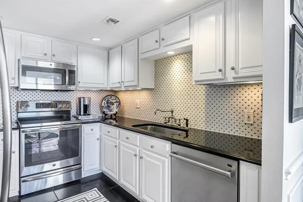 a kitchen with granite countertop white cabinets and white appliances