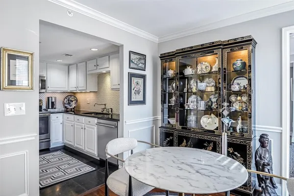 a kitchen with a stove a sink dishwasher a dining table and chairs with wooden floor