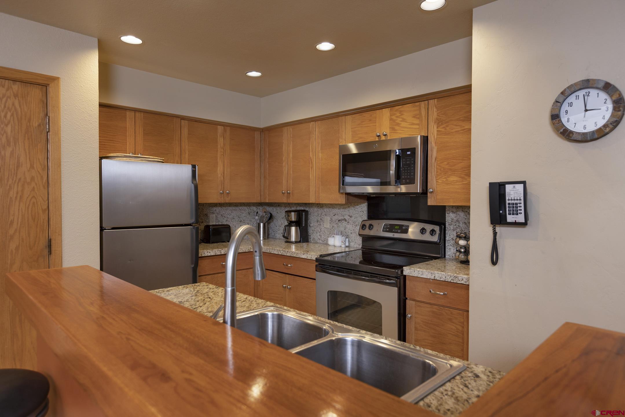 93 Needles Way, Unit 413 Durango, CO 81301 - Photo 17 of 31 a kitchen with granite countertop a refrigerator and a stove top oven
