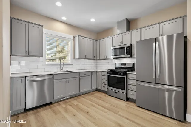 a kitchen with granite countertop stainless steel appliances a refrigerator sink and microwave