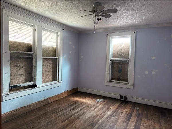 an empty room with wooden floor and windows