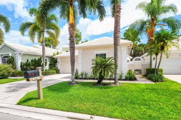 front view of a house with a yard and palm trees