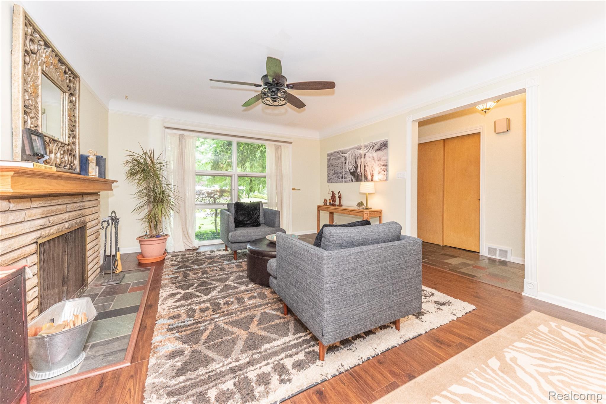 3887 Stonecrest Road West Bloomfield, MI 48322 - Photo 32 of 45 Spacious living area featuring a brick-surround fireplace with a wood mantel, wood-finish flooring, and a ceiling fan