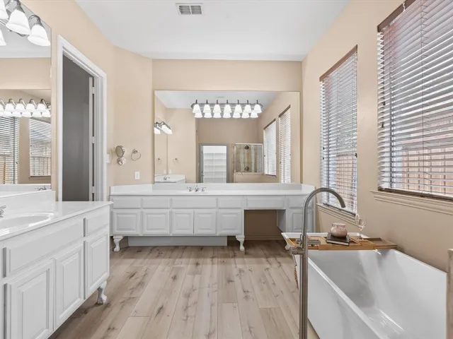 a large white kitchen with a large window a sink and cabinets