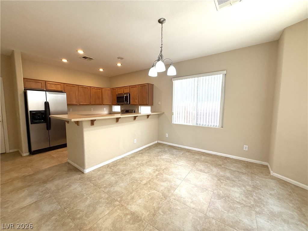 5942 Rampolla Drive Las Vegas, NV 89141 - Photo 8 of 27 An open concept kitchen and dining space with tile flooring, featuring modern appliances and a breakfast bar.