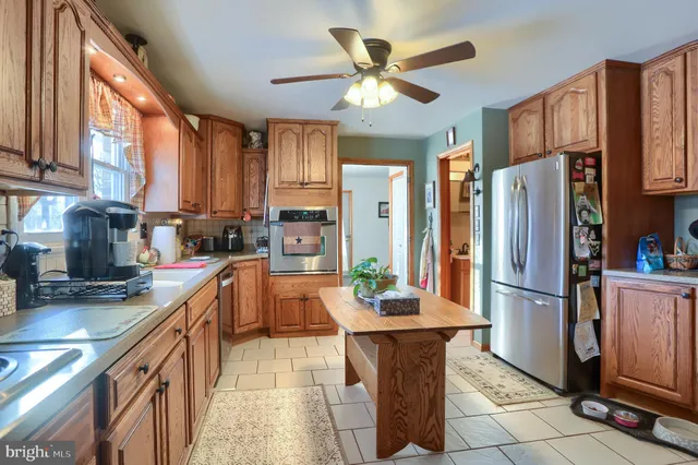 a kitchen with stainless steel appliances granite countertop a refrigerator a sink a stove and white cabinets