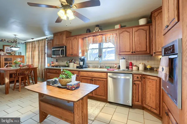 a kitchen with stainless steel appliances granite countertop a sink a stove a refrigerator cabinets and dining table