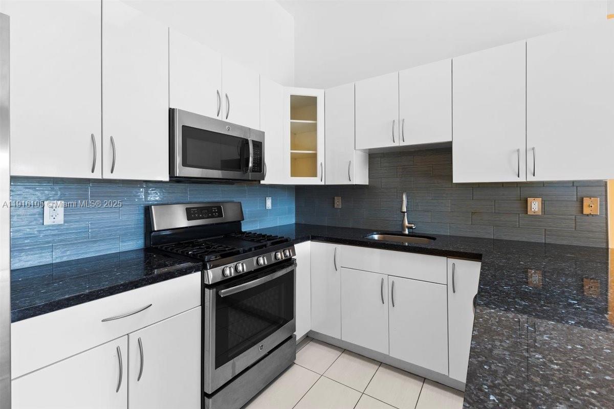 9231 Southwest 150th Avenue Miami, FL 33196 - Photo 18 of 51 a kitchen with granite countertop white cabinets and black appliances