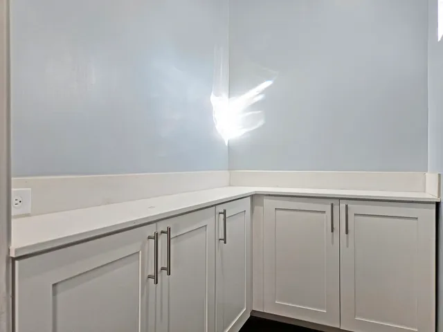 a view of a kitchen with white cabinets and wooden floor