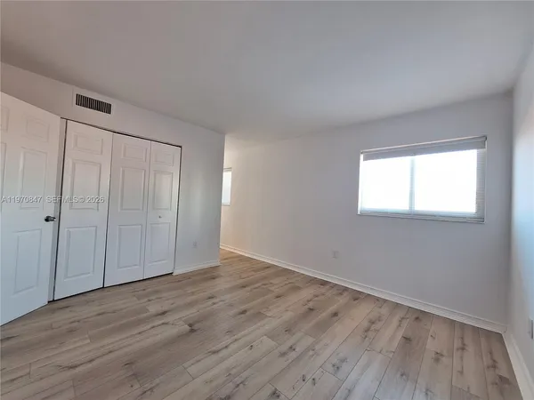 a view of a hallway with wooden floor and a window