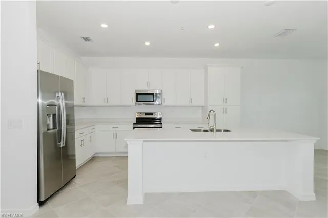 a kitchen with stainless steel appliances a refrigerator sink and white cabinets