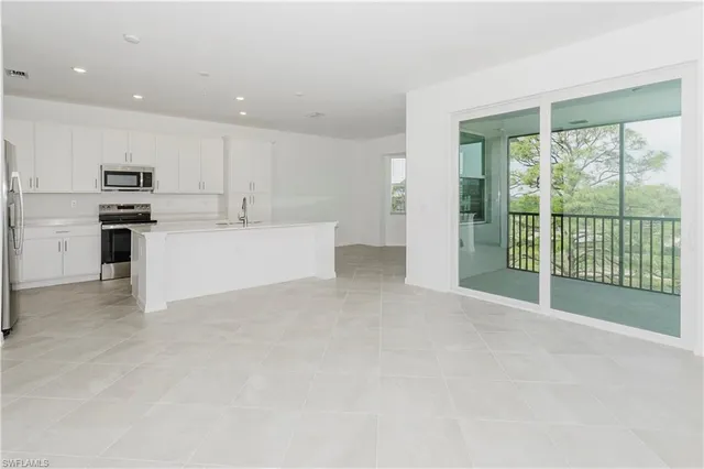 a view of kitchen with stainless steel appliances wooden floor and window