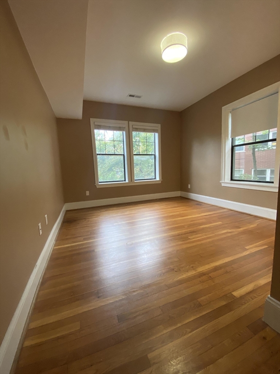 1592 Beacon Street, Unit 2 Brookline, MA 02446 - Photo 5 of 10 an empty room with wooden floor and windows