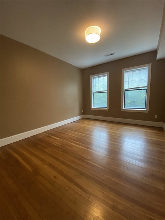 1592 Beacon Street, Unit 2 Brookline, MA 02446 - Photo 6 of 10 an empty room with wooden floor and windows