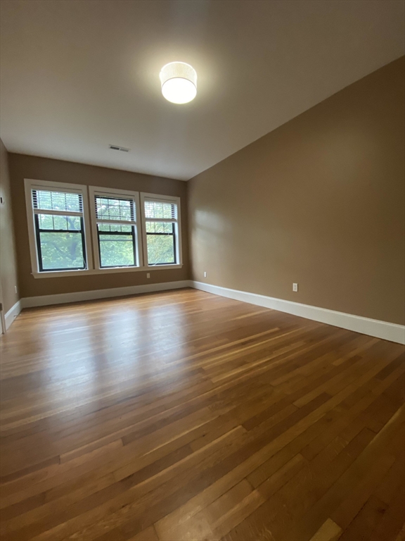 1592 Beacon Street, Unit 2 Brookline, MA 02446 - Photo 8 of 10 a view of an empty room with wooden floor and a window