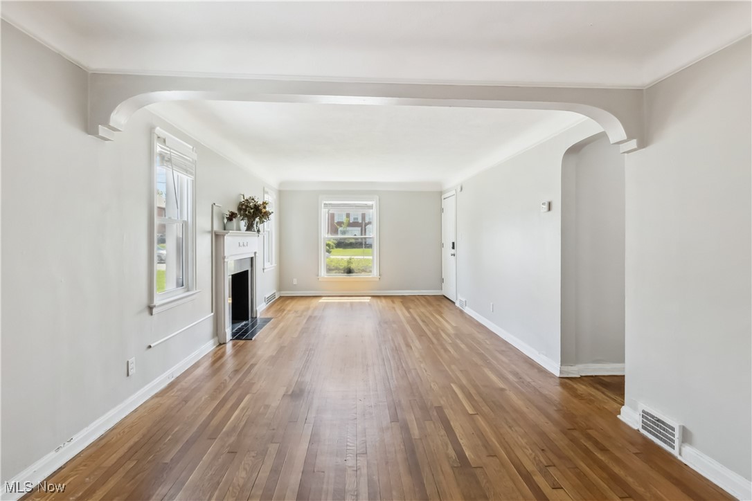13641 Cedar Road Cleveland, OH 44118 - Photo 9 of 42 Unfurnished living room featuring arched walkways, hardwood / wood-style flooring, a fireplace with flush hearth, and baseboards