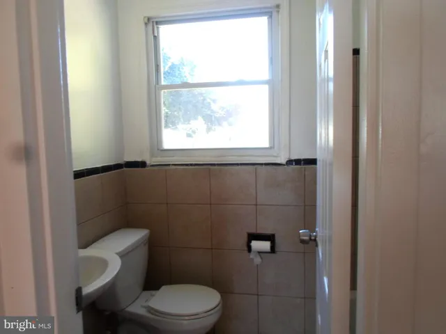 a white toilet sitting next to a window in a bathroom