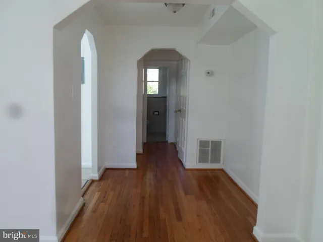 a view of a hallway with wooden floor and a bathroom
