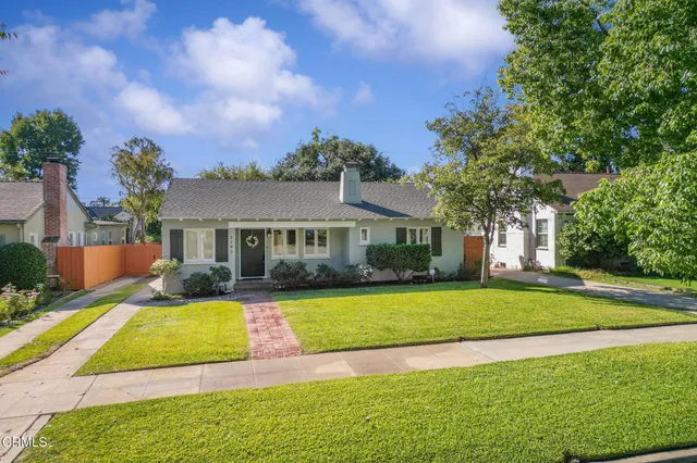 a view of a house with a big yard potted plants and large tree