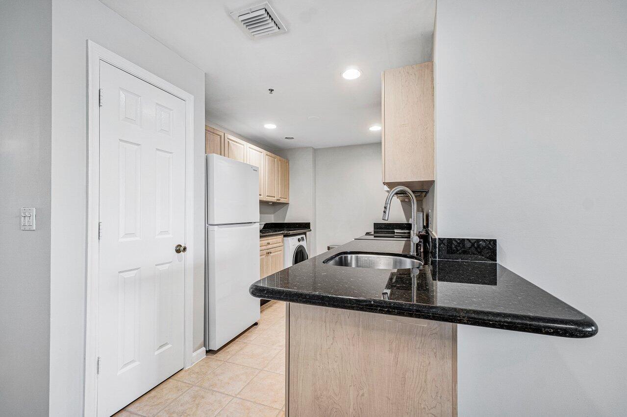 2040 Greenview Shores Boulevard, Unit 223 Wellington, FL 33414 - Photo 10 of 15 a kitchen with kitchen island a counter top space cabinets and stainless steel appliances