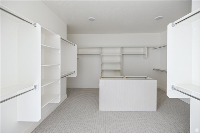 7189 South Sage Road, Unit 214 West Jordan, UT 84081 - Photo 17 of 29 Spacious walk-in closet featuring extensive built-in shelving, multiple hanging rods, a central island, recessed lighting, and patterned carpeting