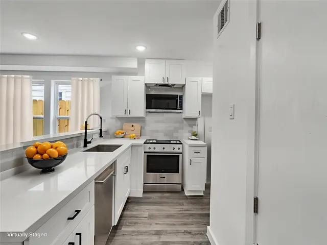 a view of kitchen with kitchen island white cabinets and wooden floor