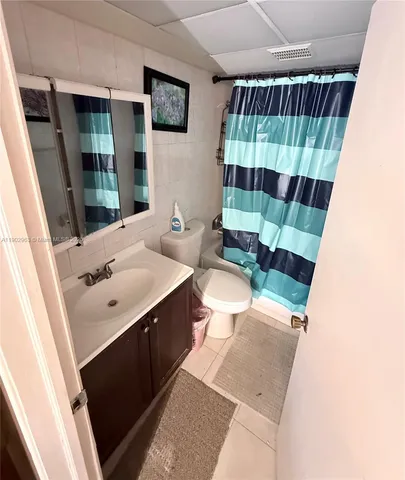 a bathroom with a sink a toilet a shower curtain and a mirror
