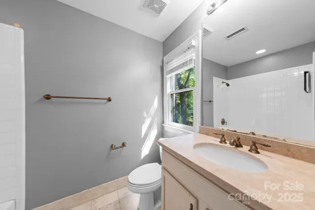 a bathroom with a granite countertop sink a mirror and a toilet