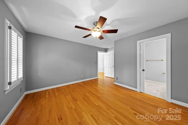a view of an empty room with window and a chandelier fan