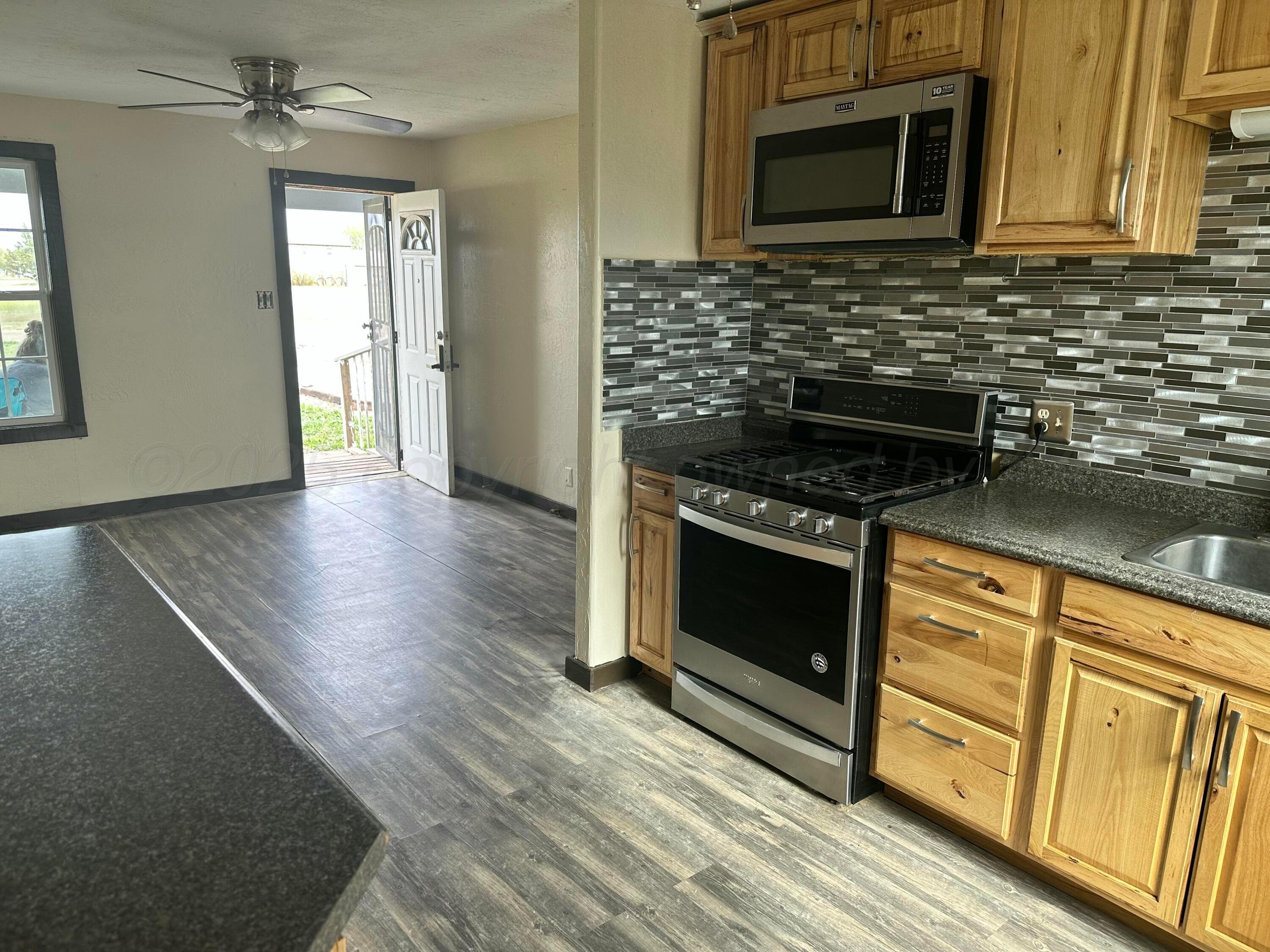 709 Flora Avenue Panhandle, TX 79068 - Photo 2 of 19 a kitchen with granite countertop a stove and a microwave