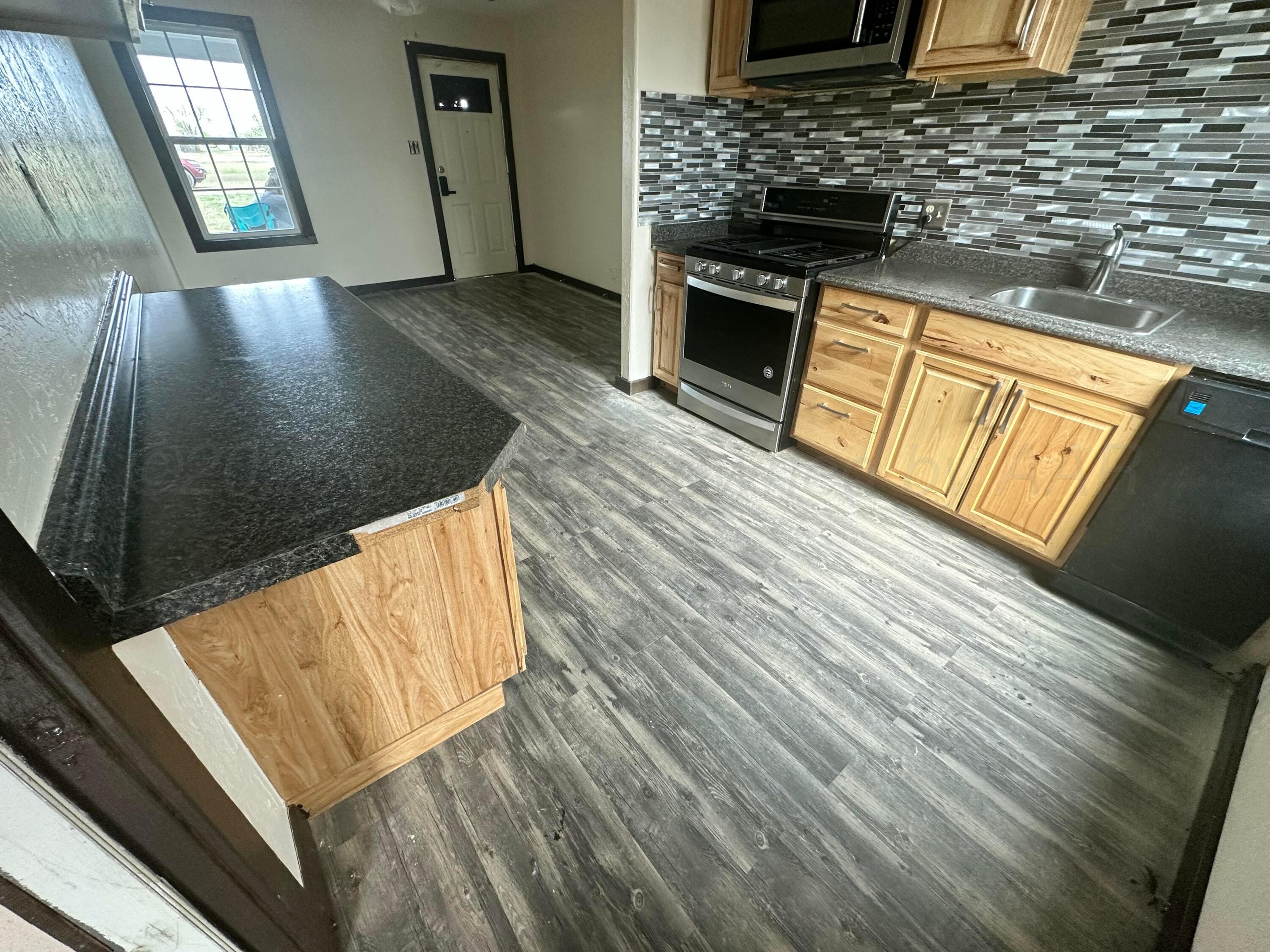 709 Flora Avenue Panhandle, TX 79068 - Photo 3 of 19 a view of a kitchen with wooden floor and a sink