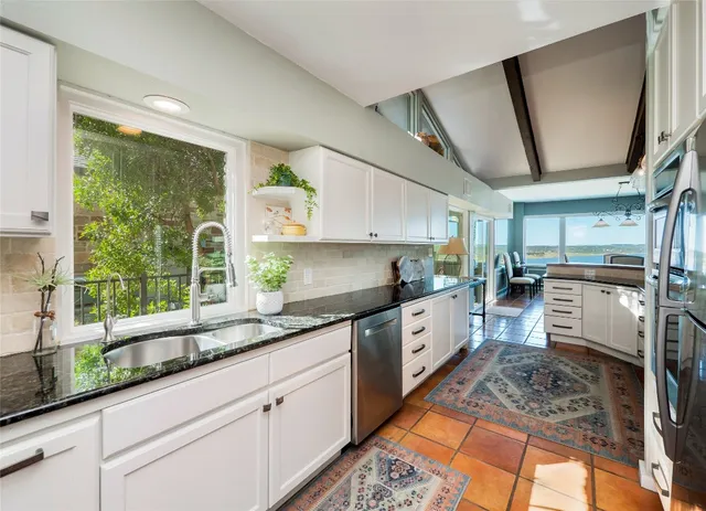 a kitchen with stainless steel appliances granite countertop a sink a stove and cabinets