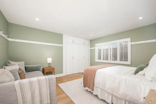 a spacious bedroom with a bed and wooden floor