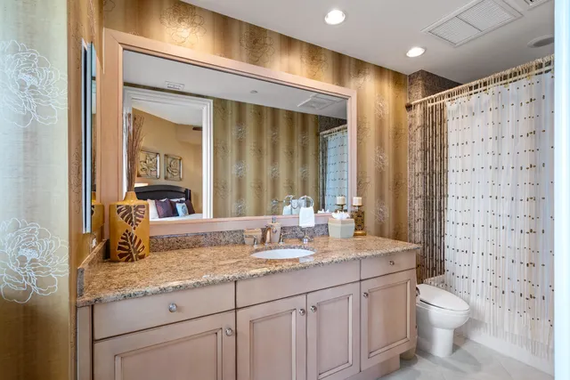 a bathroom with a granite countertop sink a toilet a mirror and shower