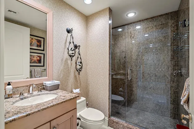 a bathroom with a granite countertop sink a toilet and shower