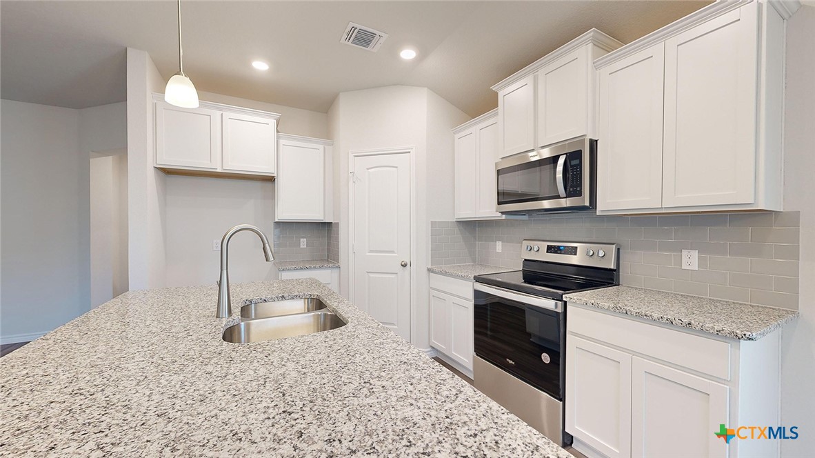 2057 Buckner Street Nolanville, TX 76559 - Photo 8 of 33 a kitchen with stainless steel appliances granite countertop a stove a sink dishwasher and a microwave oven with white cabinets